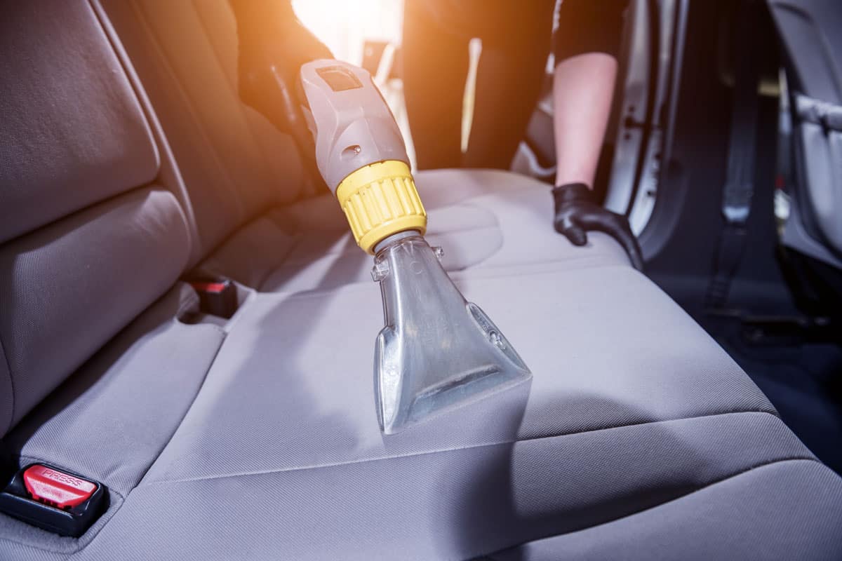 Car auto detailer using a vacuum to clean the car seat