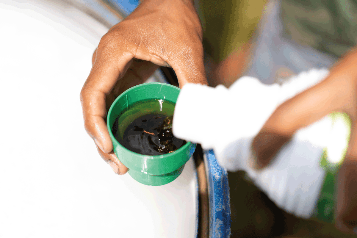 Farmer hand pouring chemical insecticide liquid acid into bottle cap